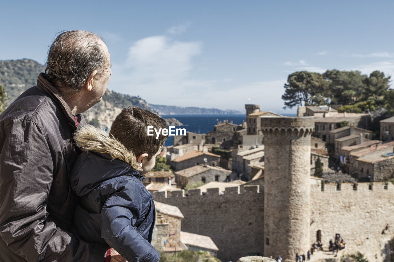 Grandson and grandfather looking at view of tossa de mar