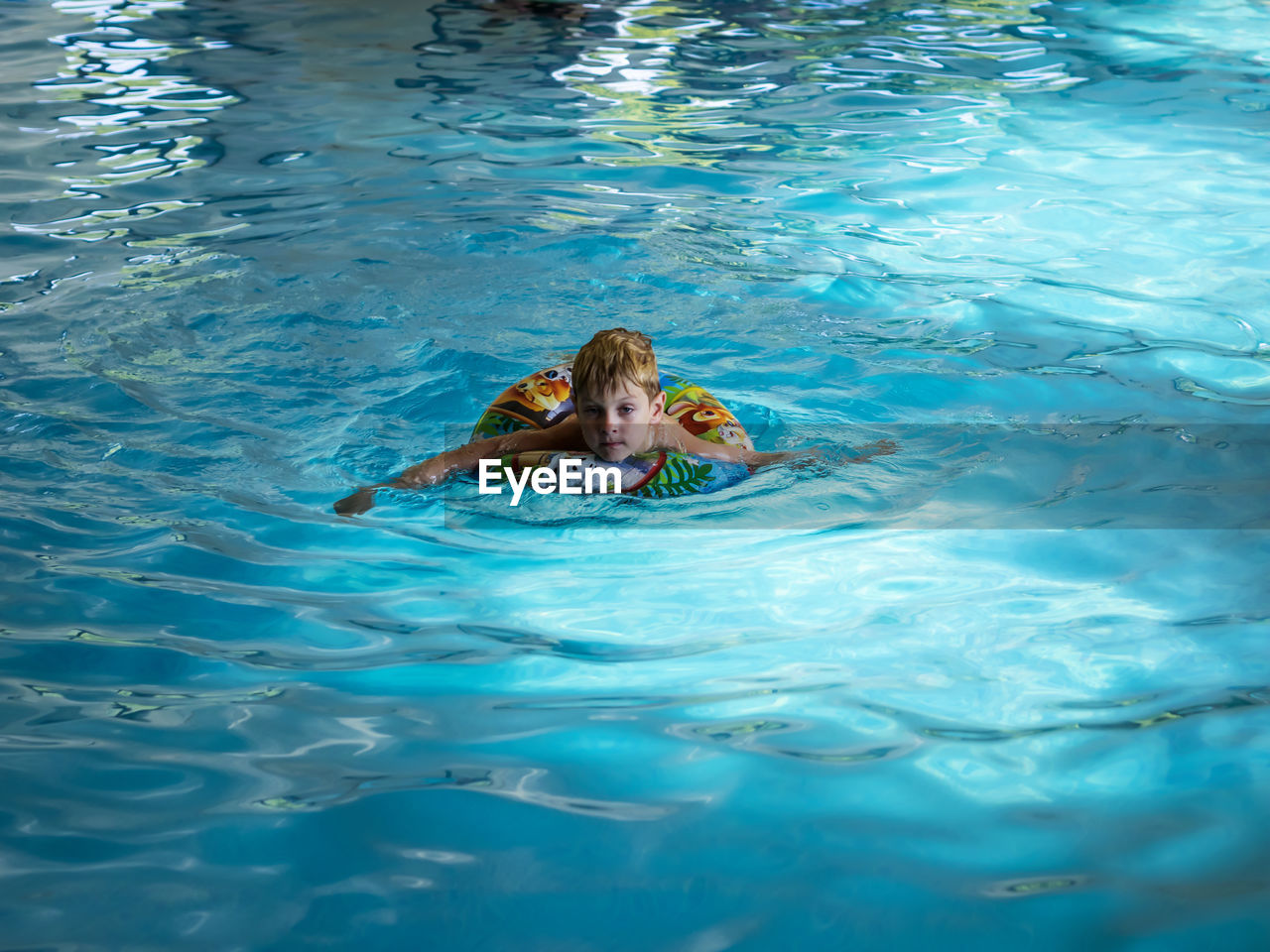 High angle portrait of boy with inflatable ring swimming in pool