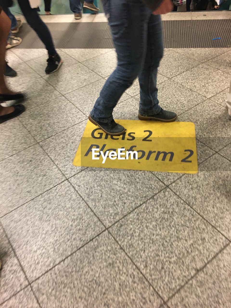 LOW SECTION OF MAN WITH TEXT ON TILED FLOOR