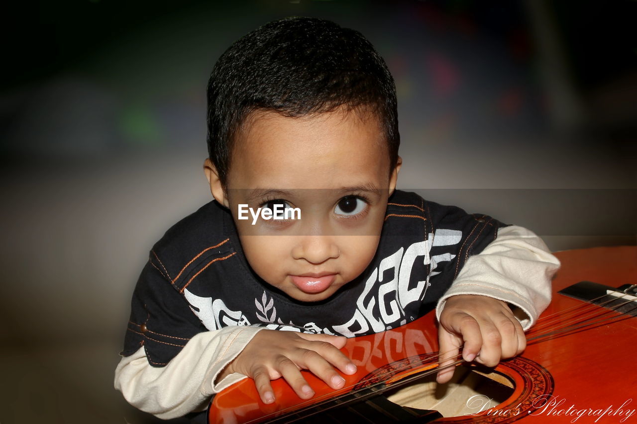 CLOSE-UP PORTRAIT OF BOY PLAYING WITH BALL AT HOME