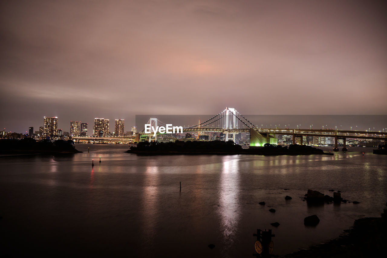 Illuminated rainbow bridge over tokyo bay against sky at dusk