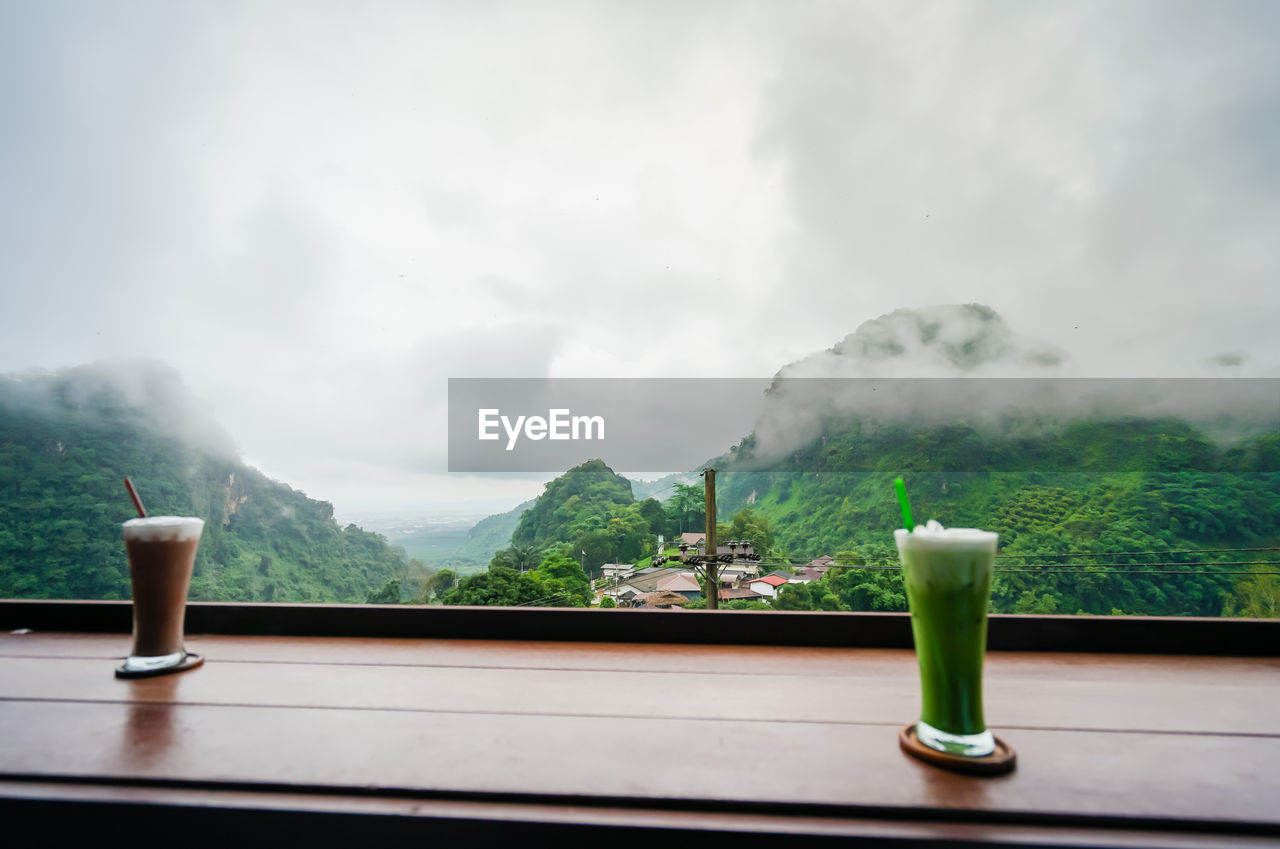 WINE GLASS ON TABLE AGAINST MOUNTAINS