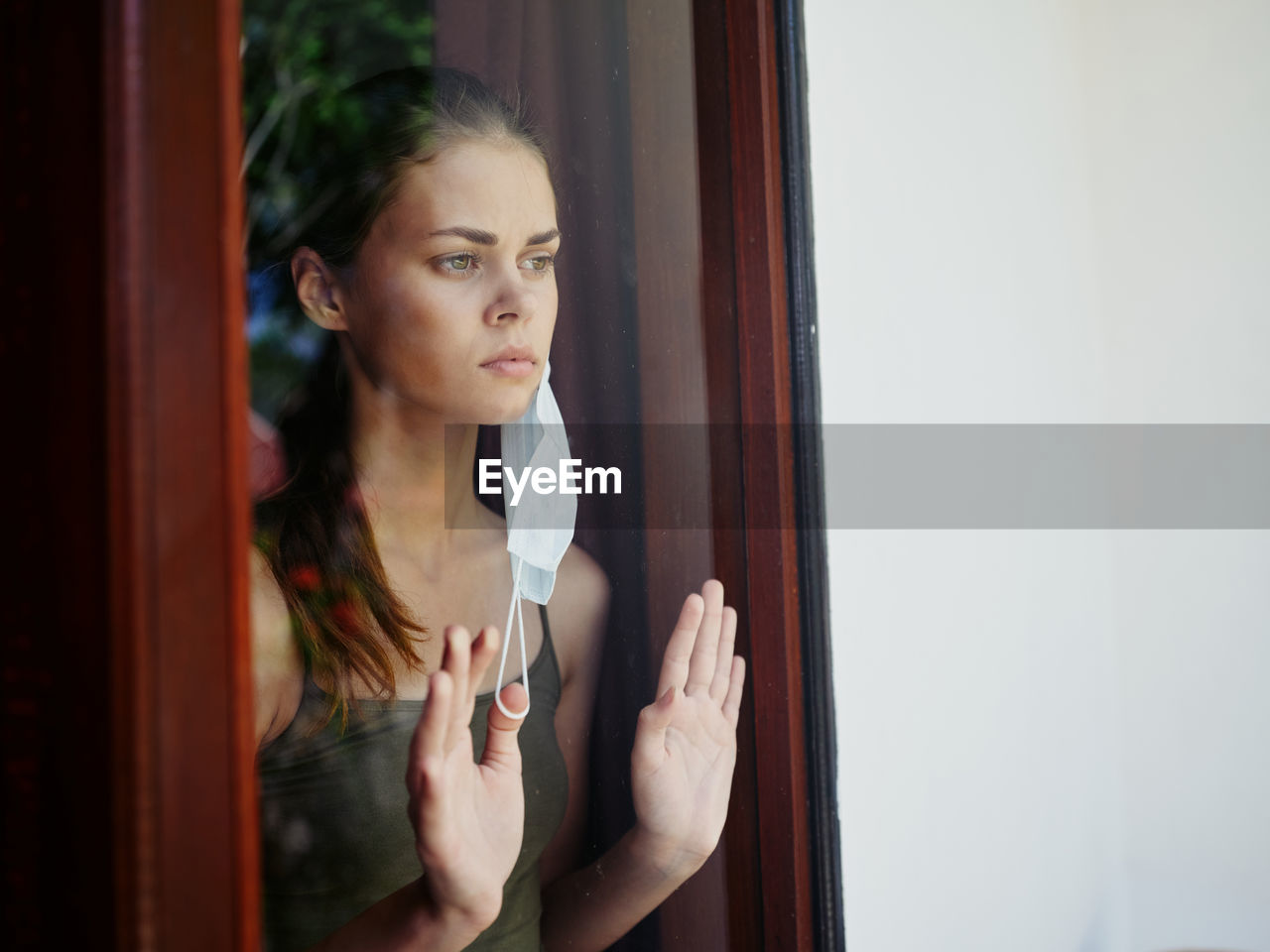 PORTRAIT OF YOUNG WOMAN STANDING AGAINST DOOR