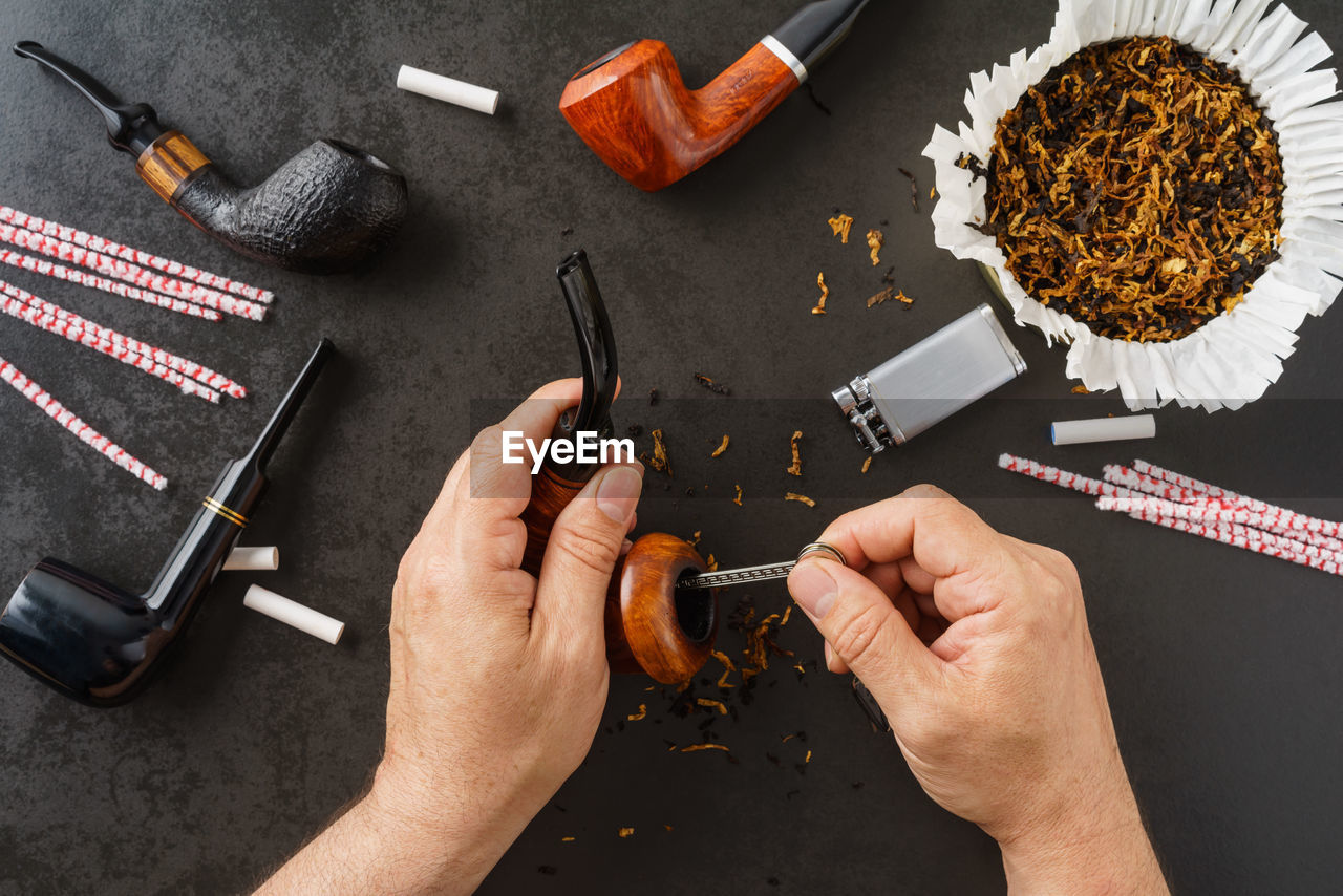 Cropped image of hands cleaning smoking pipe at table
