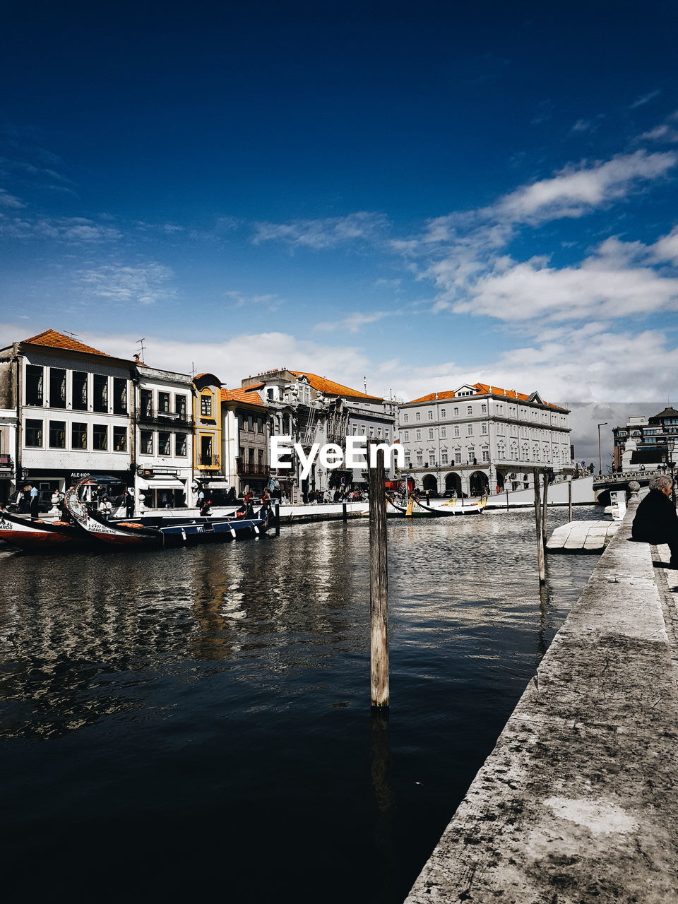 SAILBOATS MOORED IN RIVER AGAINST BUILDINGS IN CITY