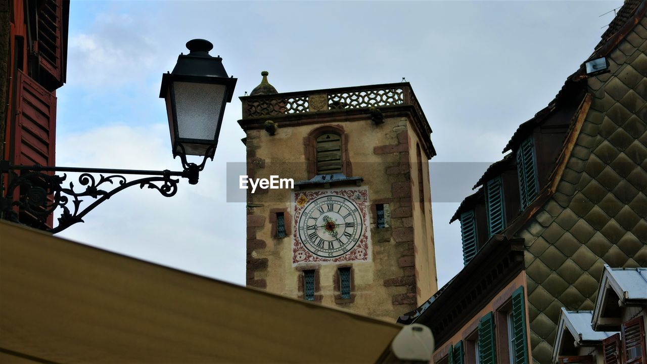 LOW ANGLE VIEW OF CLOCK TOWER BY BUILDING AGAINST SKY