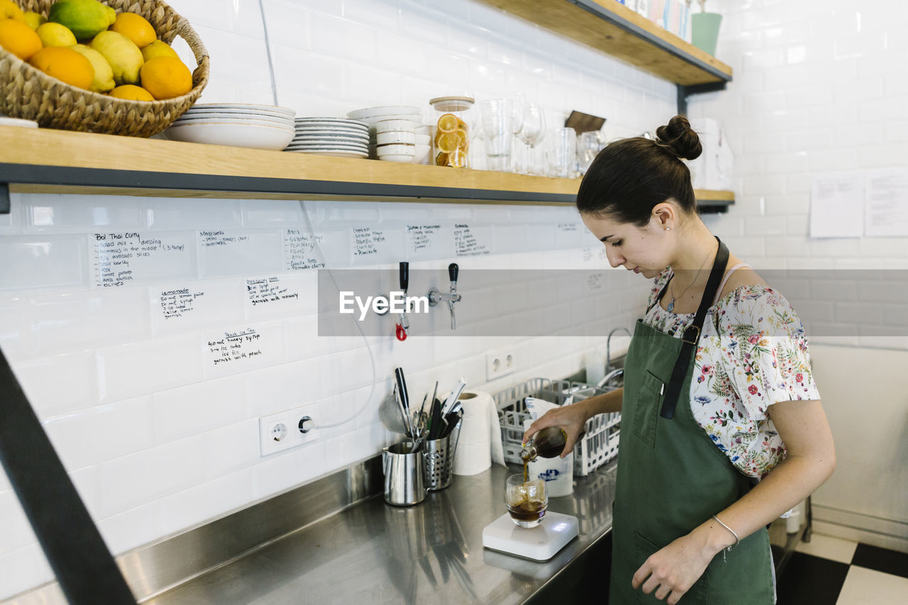 Barista making cold brew coffee while standing in kitchen at coffee shop