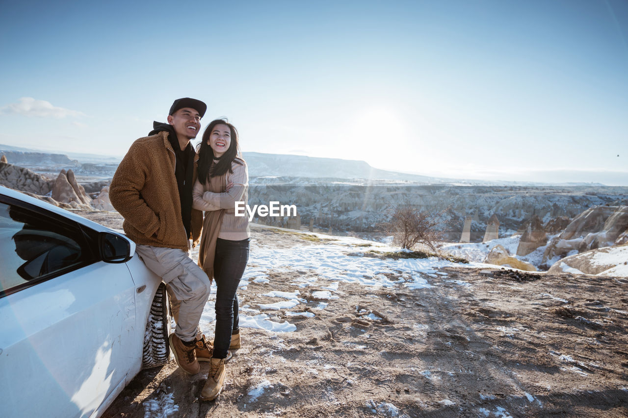 side view of couple sitting on snow