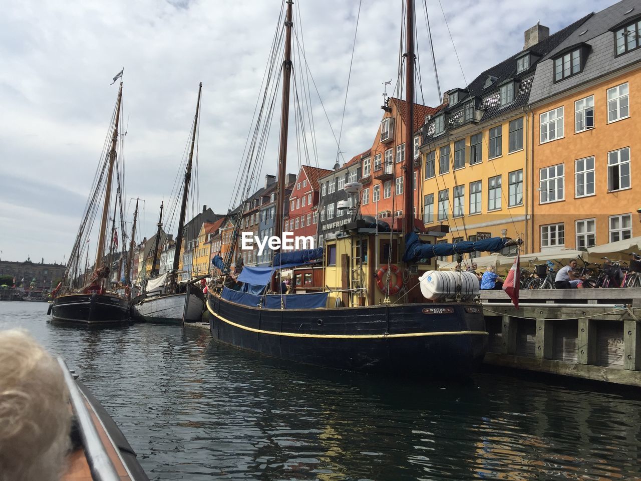 SAILBOATS MOORED IN CANAL AGAINST SKY IN CITY