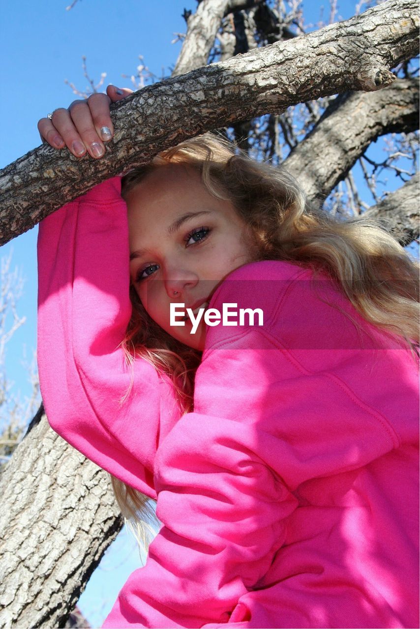 Portrait of young woman sitting on tree