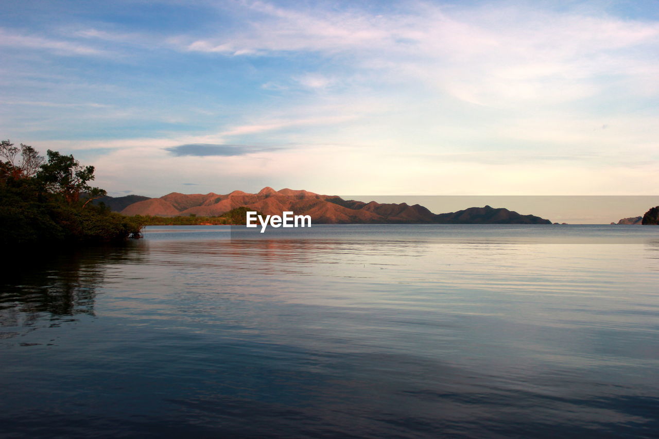 Scenic view of lake by mountains against sky