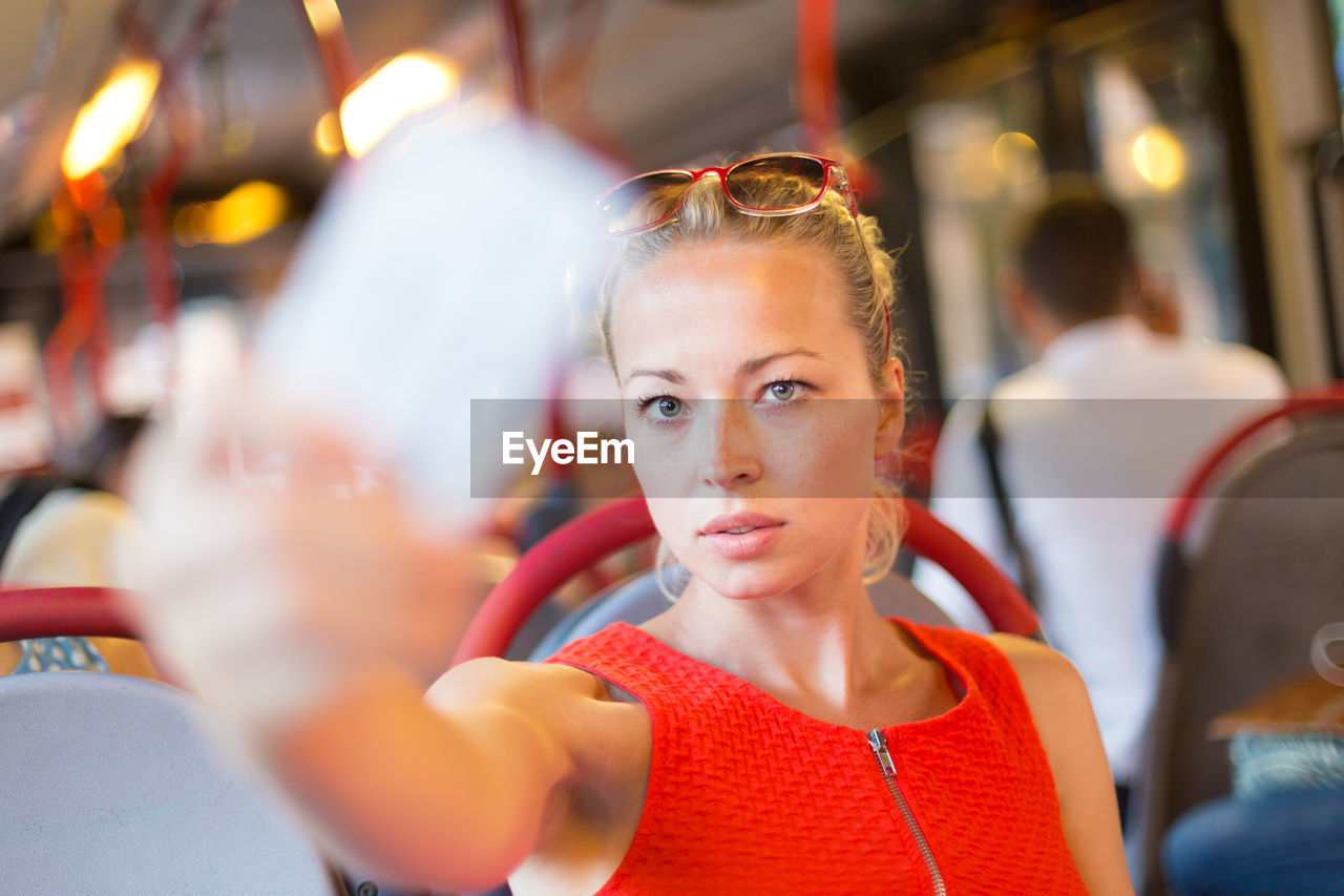 Portrait of beautiful woman taking selfie sitting at bus