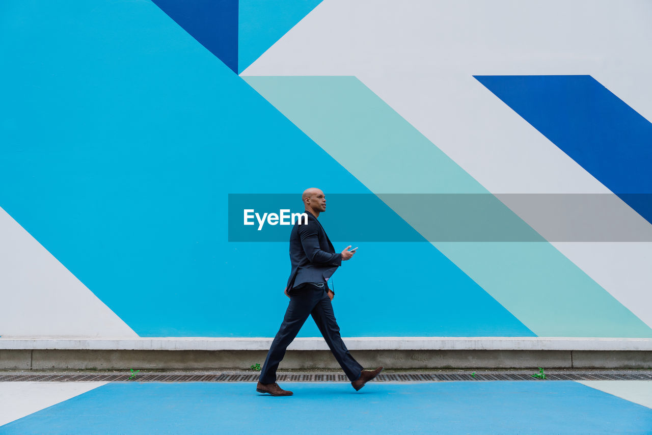 full length of man standing against blue wall