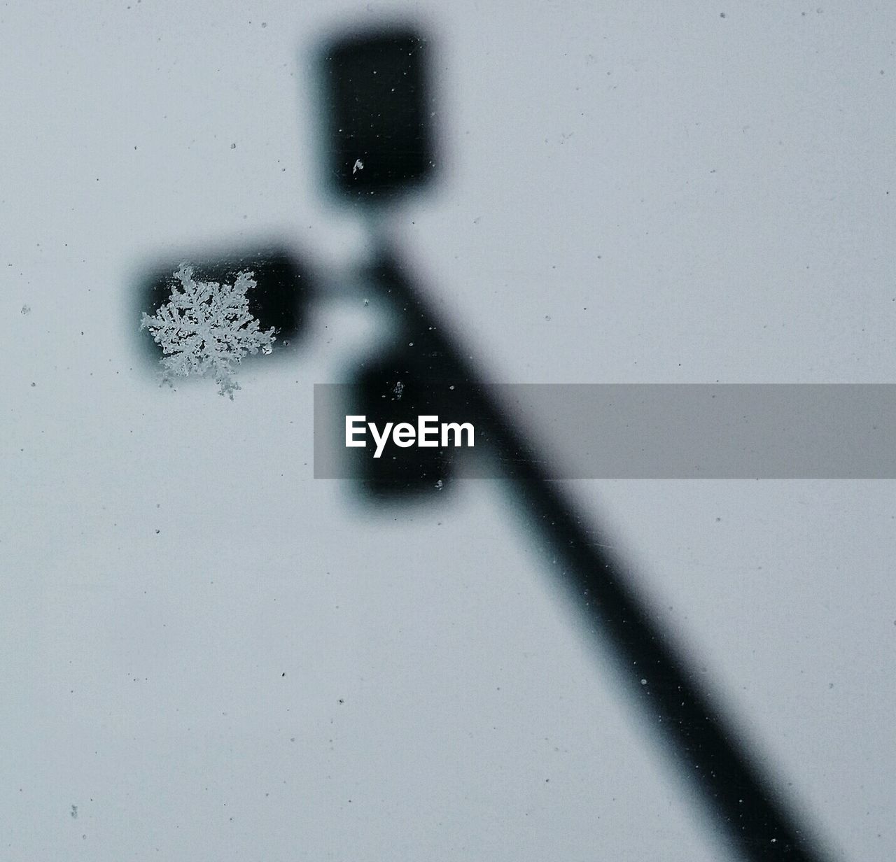 Close-up of snowflake on glass window against sky