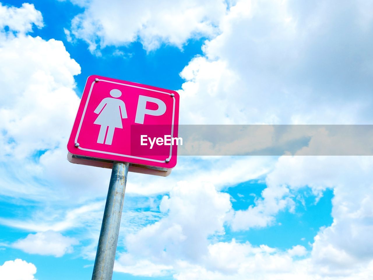 Low angle view of road sign against blue cloudy sky