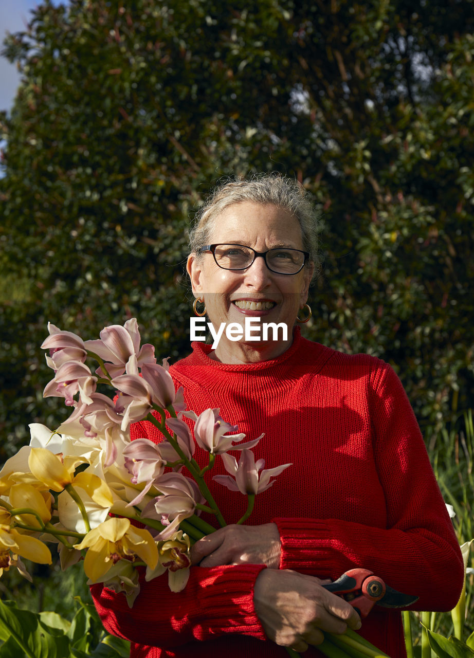 Older woman holding bouquet of fresh cut flowers in her garden