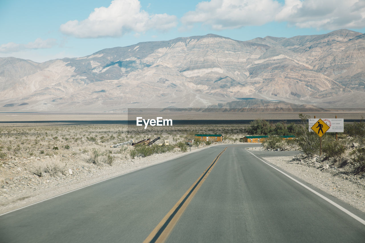 Road by mountains against sky