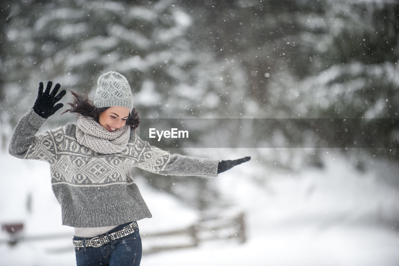 Happy woman wearing knitwear dancing in the snow