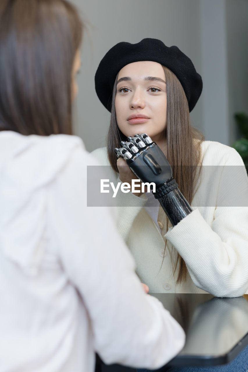 A european woman with a bionic prosthesis on her arm is talking to friends in a public place