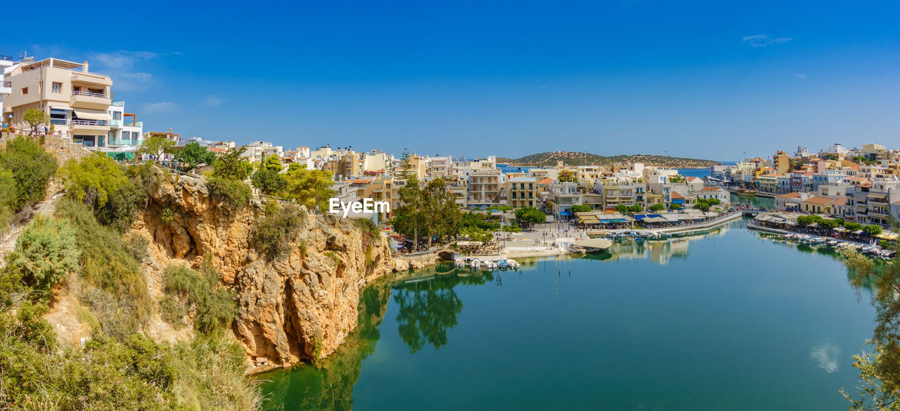 High angle view of houses by sea against clear blue sky