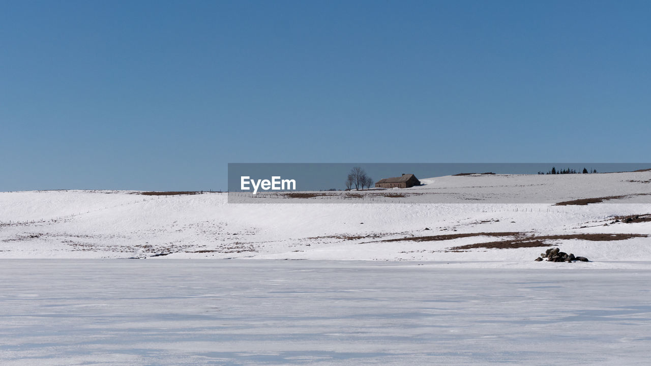 Scenic view of snow covered land against clear blue sky