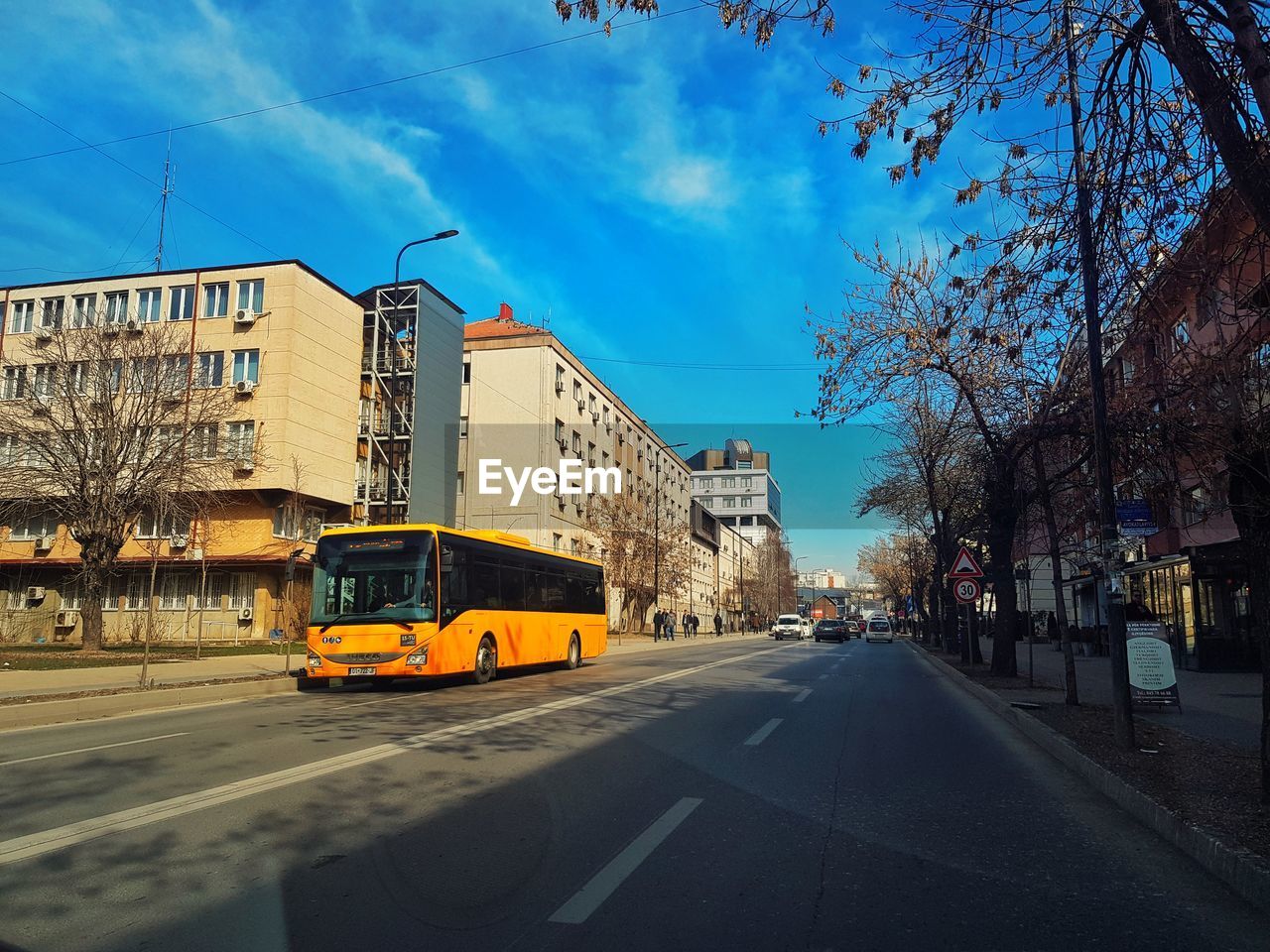 CARS ON ROAD BY BUILDINGS AGAINST SKY