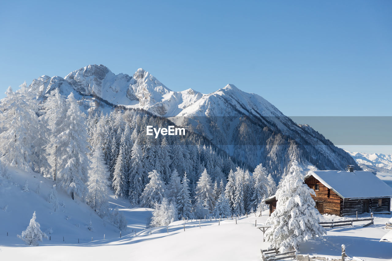 Winter nature landscape with snow covered traditional wooden chalet. copy space