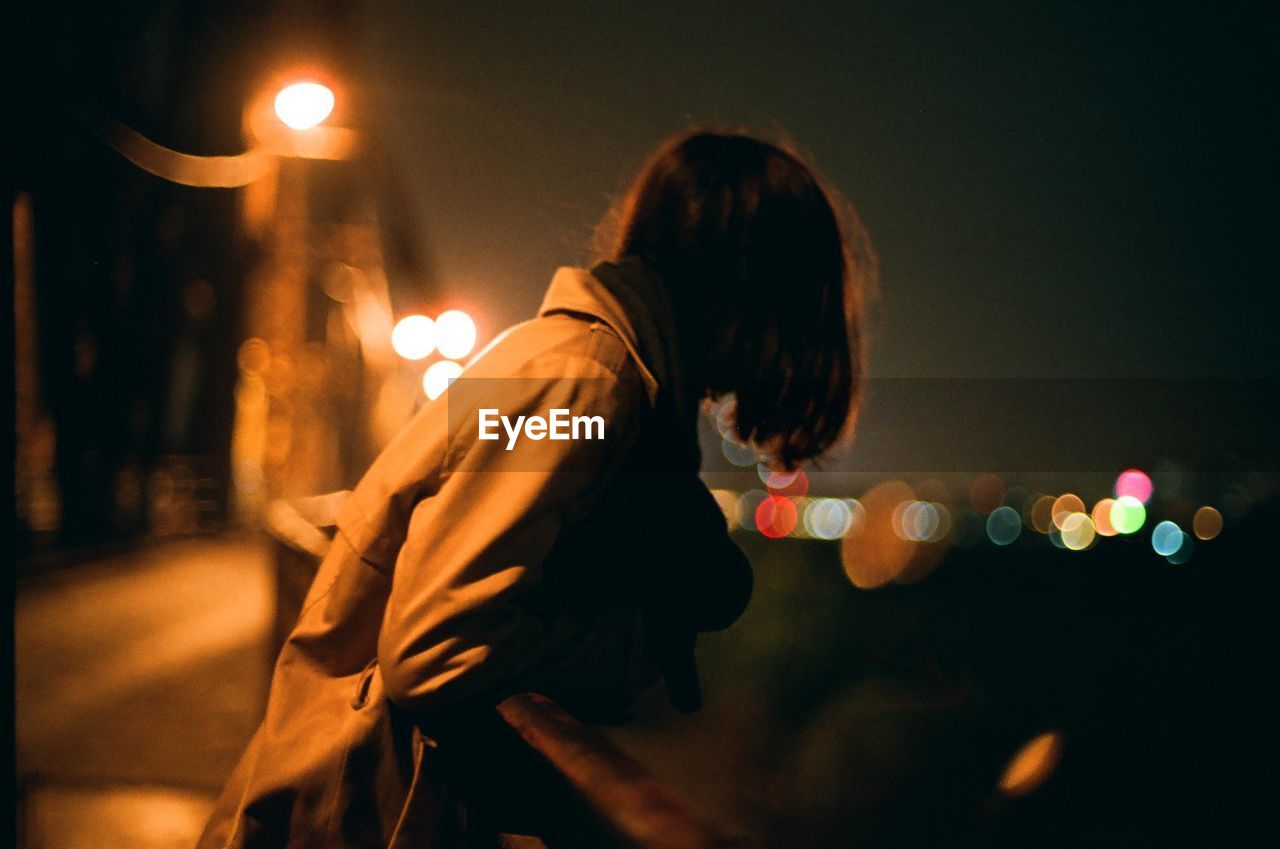 Woman leaning on railing at night