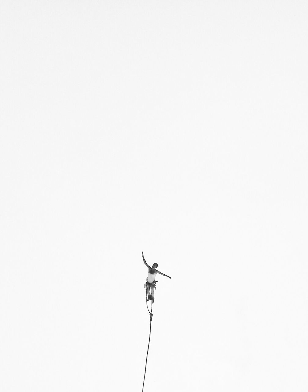 Low angle view of man bungee jumping against sky