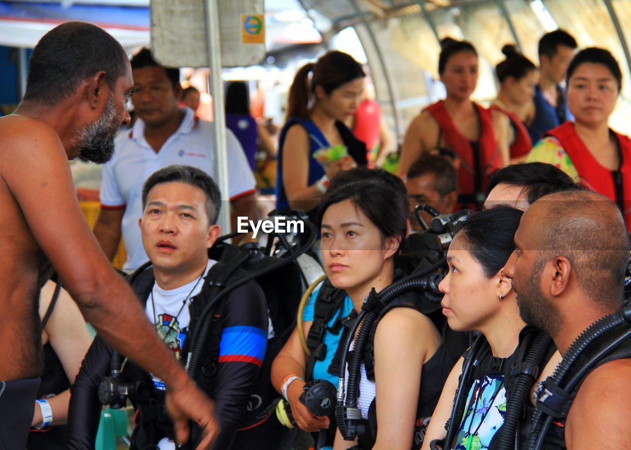 People with scuba tanks listening to instructor