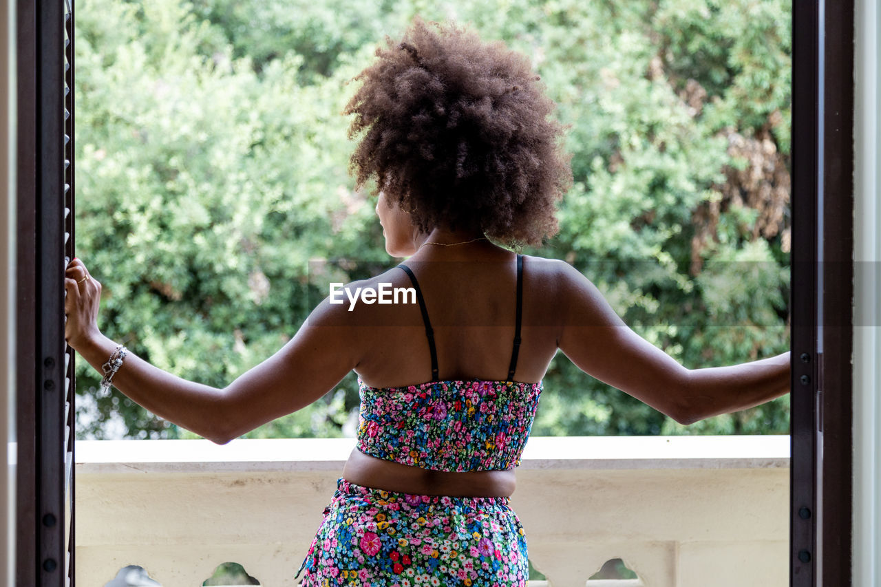 Rear view of woman looking through window