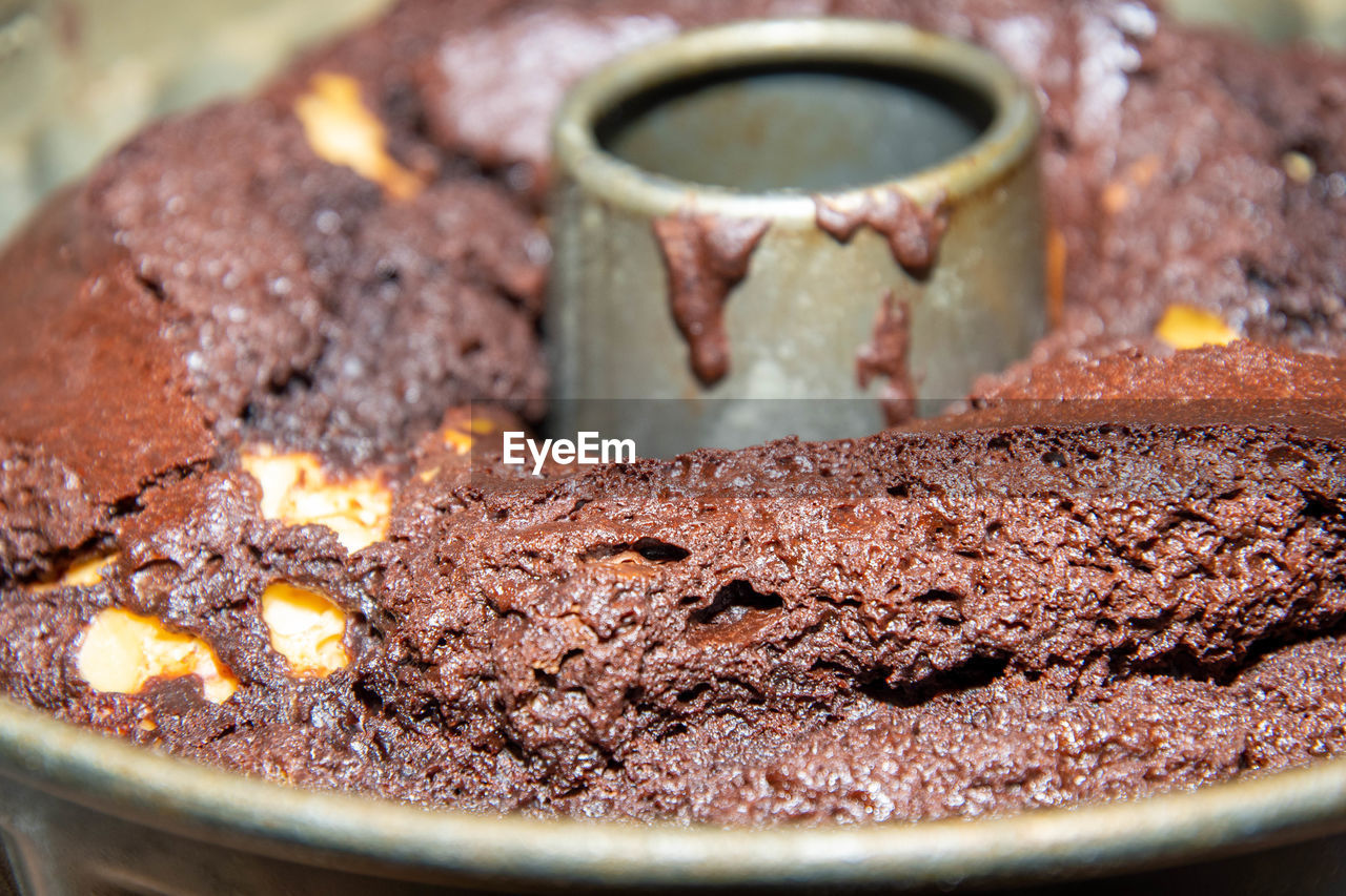 CLOSE-UP OF CHOCOLATE CAKE ON RUSTY METALLIC CONTAINER