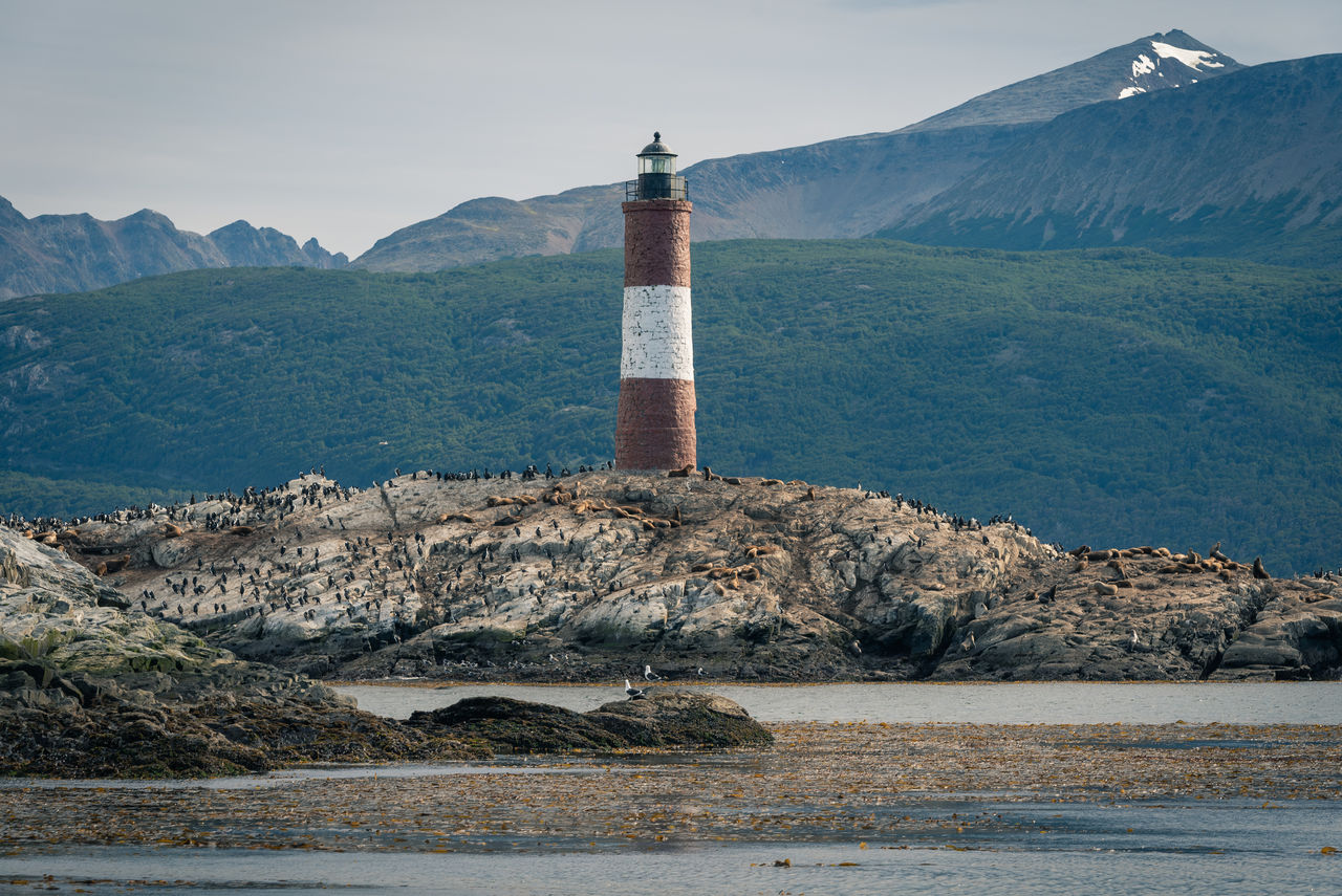 LIGHTHOUSE BY SEA AGAINST MOUNTAIN