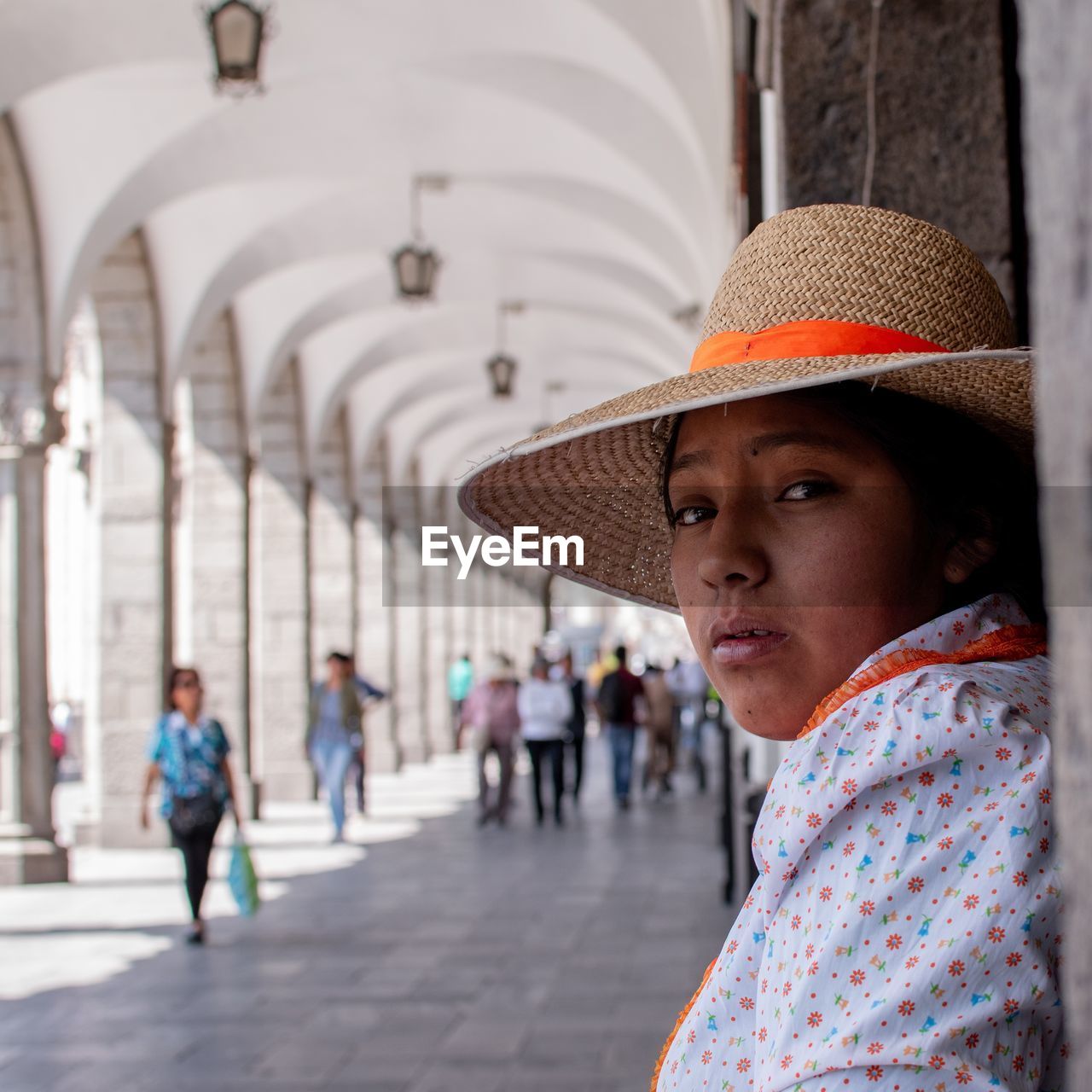 Portrait of young woman wearing hat while standing in corridor