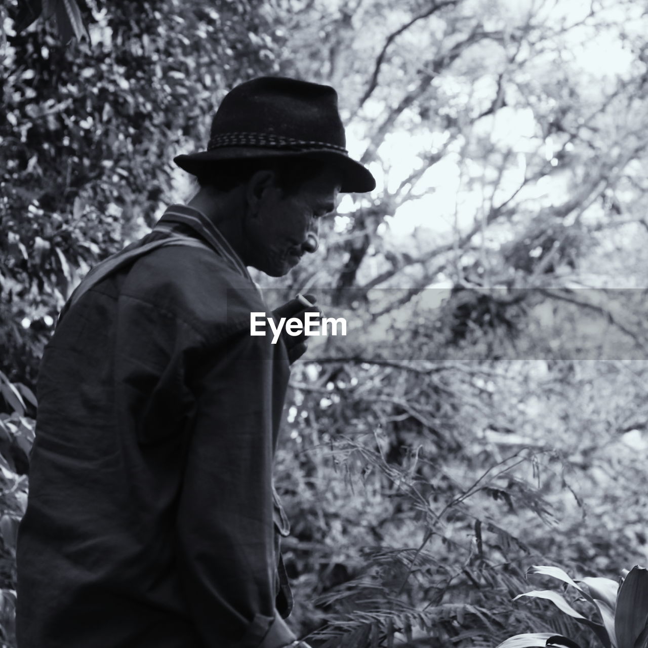 Side view of mature man wearing hat standing in forest