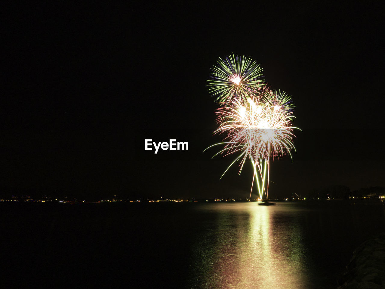 Firework display over river against sky at night