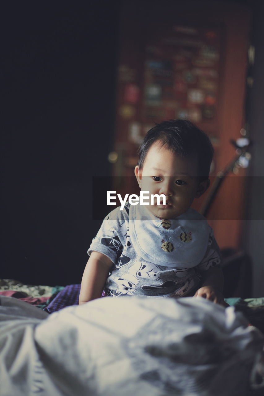 Boy sitting on bed at home