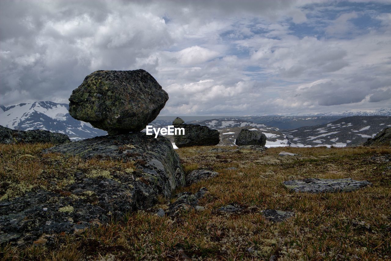 Rocks on mountains against cloudy sky during winter