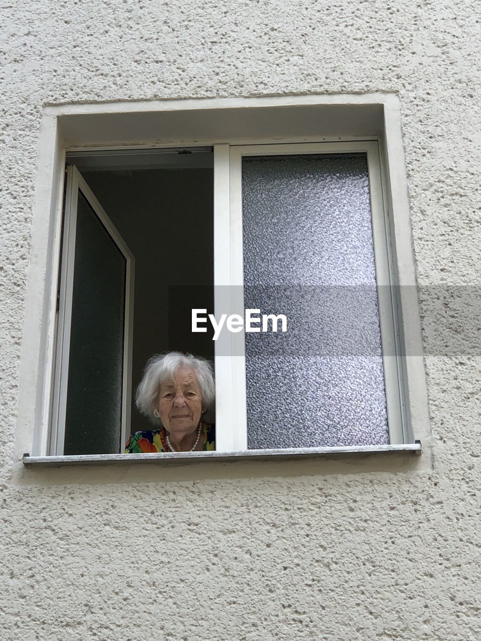 Portrait of woman looking through window of building