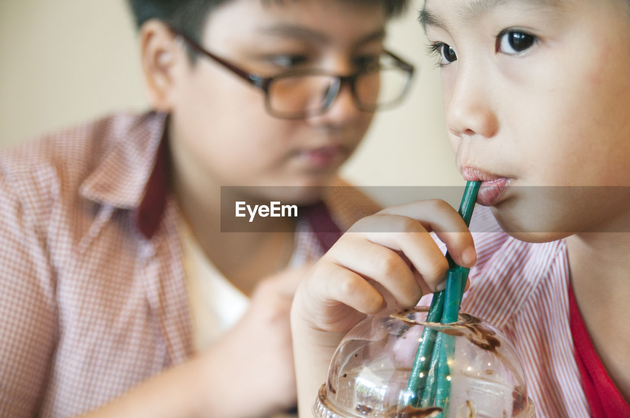 Close-up of boy drinking drink with straw