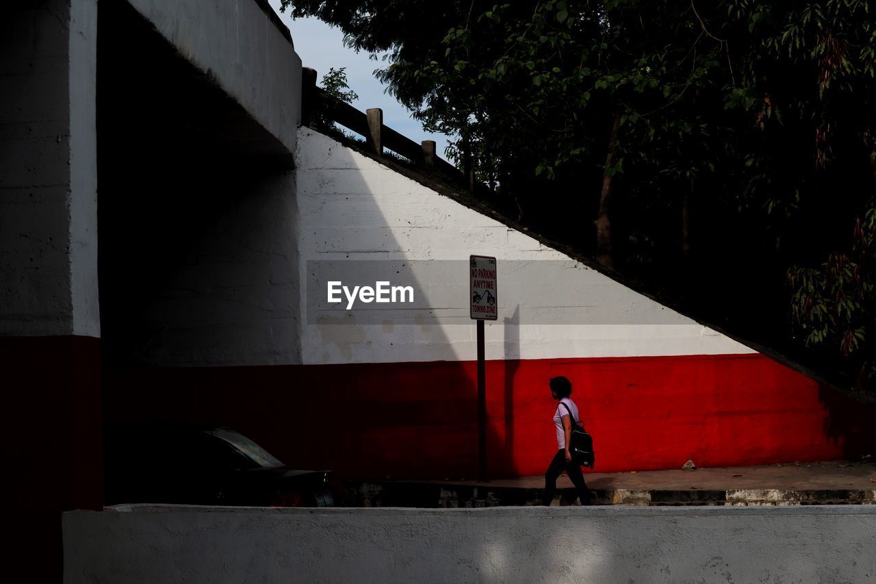 MAN STANDING BY BICYCLE AGAINST WALL