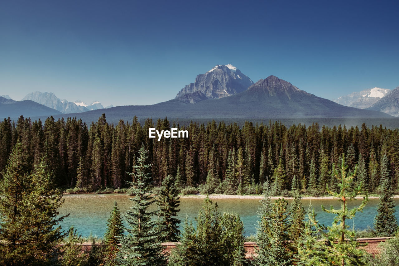 Scenic view of lake and mountains against clear blue sky