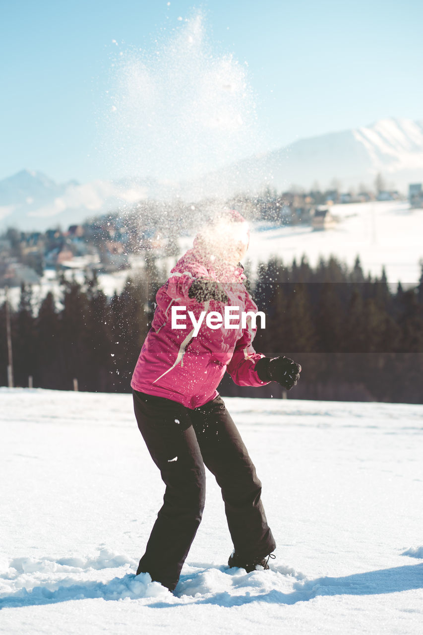 Full length of woman throwing snow during winter