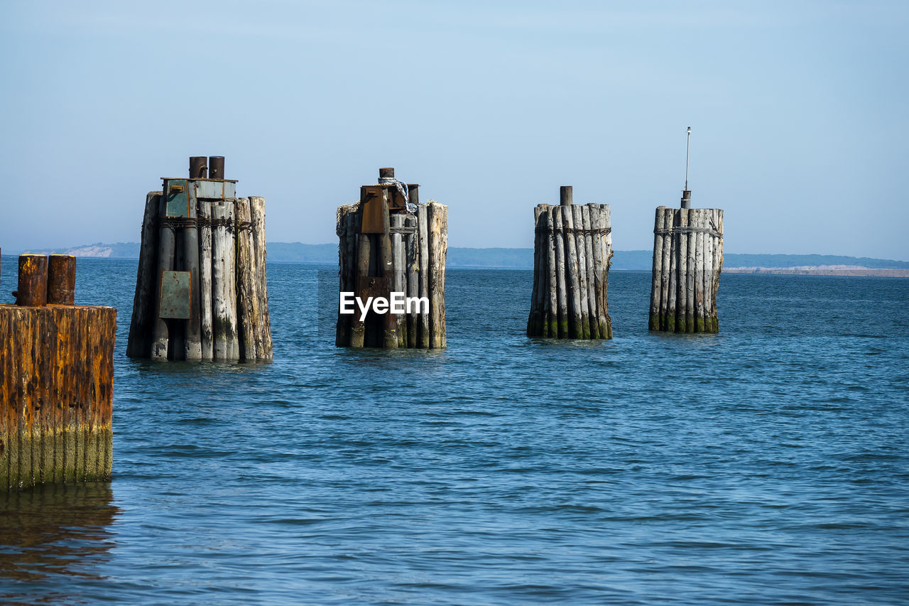 WOODEN POSTS IN SEA AGAINST SKY