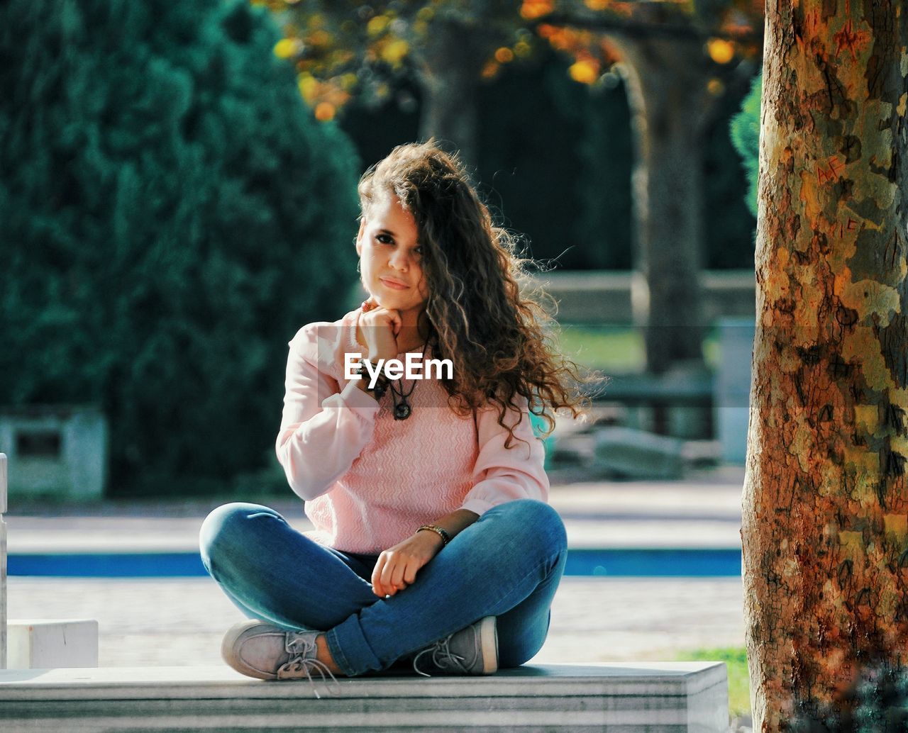 Portrait of young woman sitting by tree