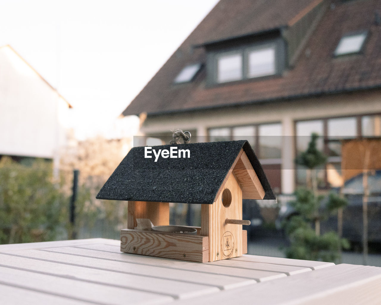 Bird house against real house on a sunny spring day