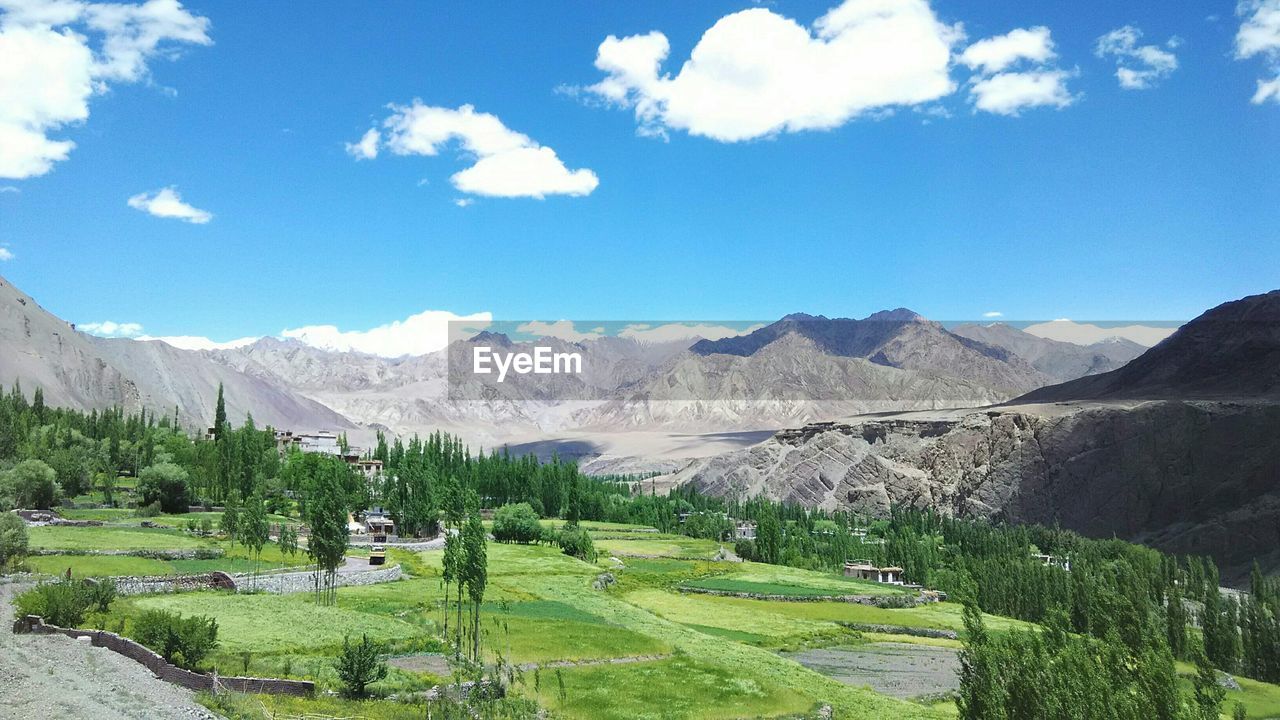 Landscape by mountains against blue sky