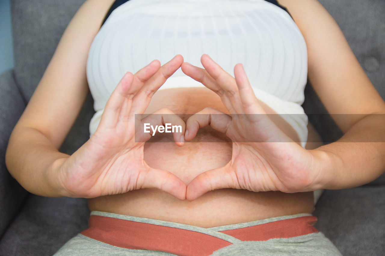 MIDSECTION OF WOMAN SITTING ON HEART SHAPE