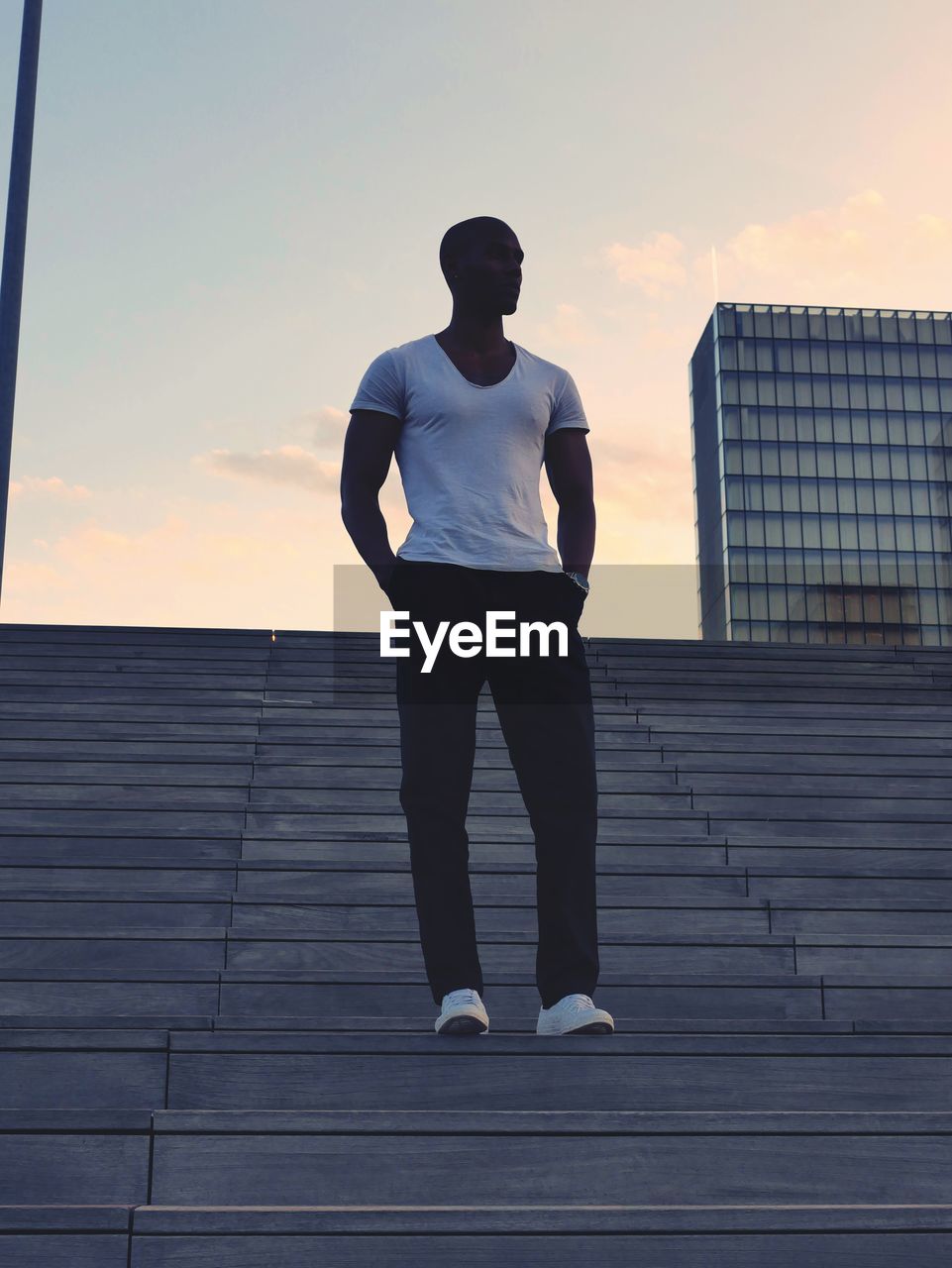 Low angle view of man standing on steps against sky during sunset