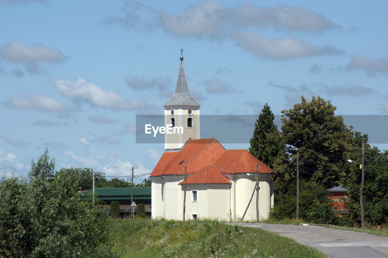 architecture, built structure, building exterior, place of worship, plant, building, religion, sky, belief, tree, nature, cloud, spirituality, tower, travel destinations, no people, history, the past, day, catholicism, rural area, outdoors, grass, landscape, travel, land, spire, tourism, cross, city